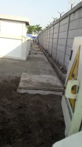 Jalur beton yang sudah selesai memanjang di sisi dinding pembatas, dengan rambu peringatan berdiri di ujung terdekat.