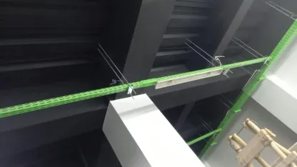 Tray kabel hijau digantung pada penggantung di rongga plafon, tepat di atas drop ceiling putih.