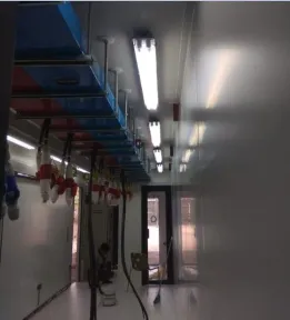 Interior kontainer yang sudah terbangun: tray kabel dan pipa di langit-langit memanjang sepanjang lorong putih menuju pintu berkaca.