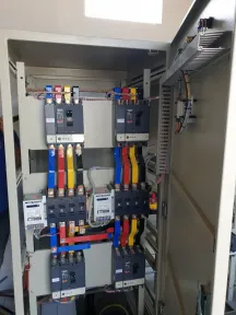 Panel tegangan rendah dalam keadaan terbuka, pemutus arus tipe MCCB terhubung ke busbar tembaga lewat kabel merah, kuning, dan biru.