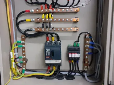 Busbar pembumian tembaga di dalam panel, dengan penghantar hijau-kuning, satu pemutus arus, dan penangkal surja yang terhubung padanya.