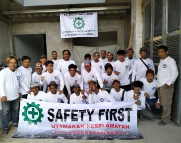 Tim proyek berkumpul untuk foto bersama sambil membentangkan spanduk Safety First.