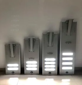 Empat lampu jalan tenaga surya terpadu dengan ukuran bertingkat disandarkan berjajar ke dinding.